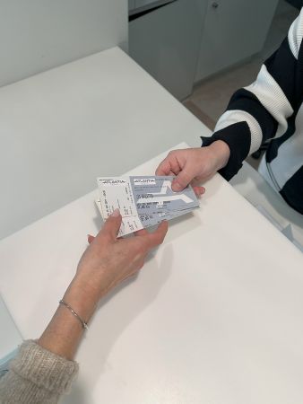 2 mains qui s'échangent des billets de spectacle à l'accueil du Palais des congrès de la Baule. Achat auprès de la réceptionniste qui est en charge des vente de billets sur place