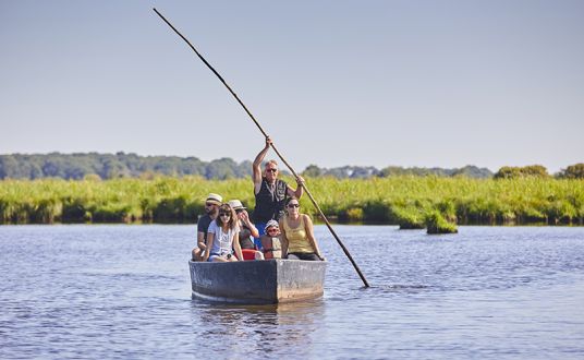 Photo d'un petit groupe sur une barque en balade sur un canal au coeur du parc régional de la Brière près de La Baule