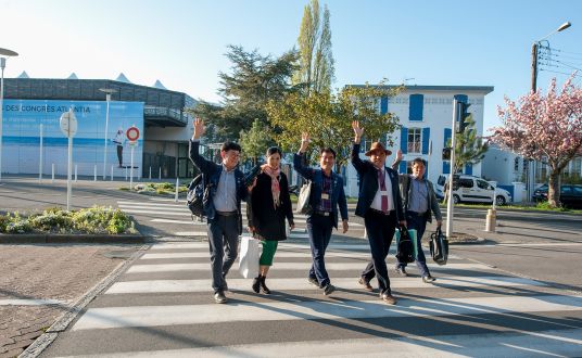 Groupe de personnes traversant la rue sur passage piéton devant le Palais des Congrès de la Baule