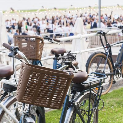 Photo d'un vélo en premier plan devant une plage remplis de convives et décoré pour un événement privé organisé sur la Plage par la Baule Evénements