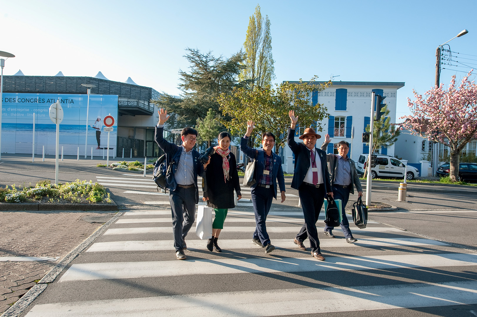 Groupe de personnes traversant la rue sur passage piéton devant le Palais des Congrès de la Baule