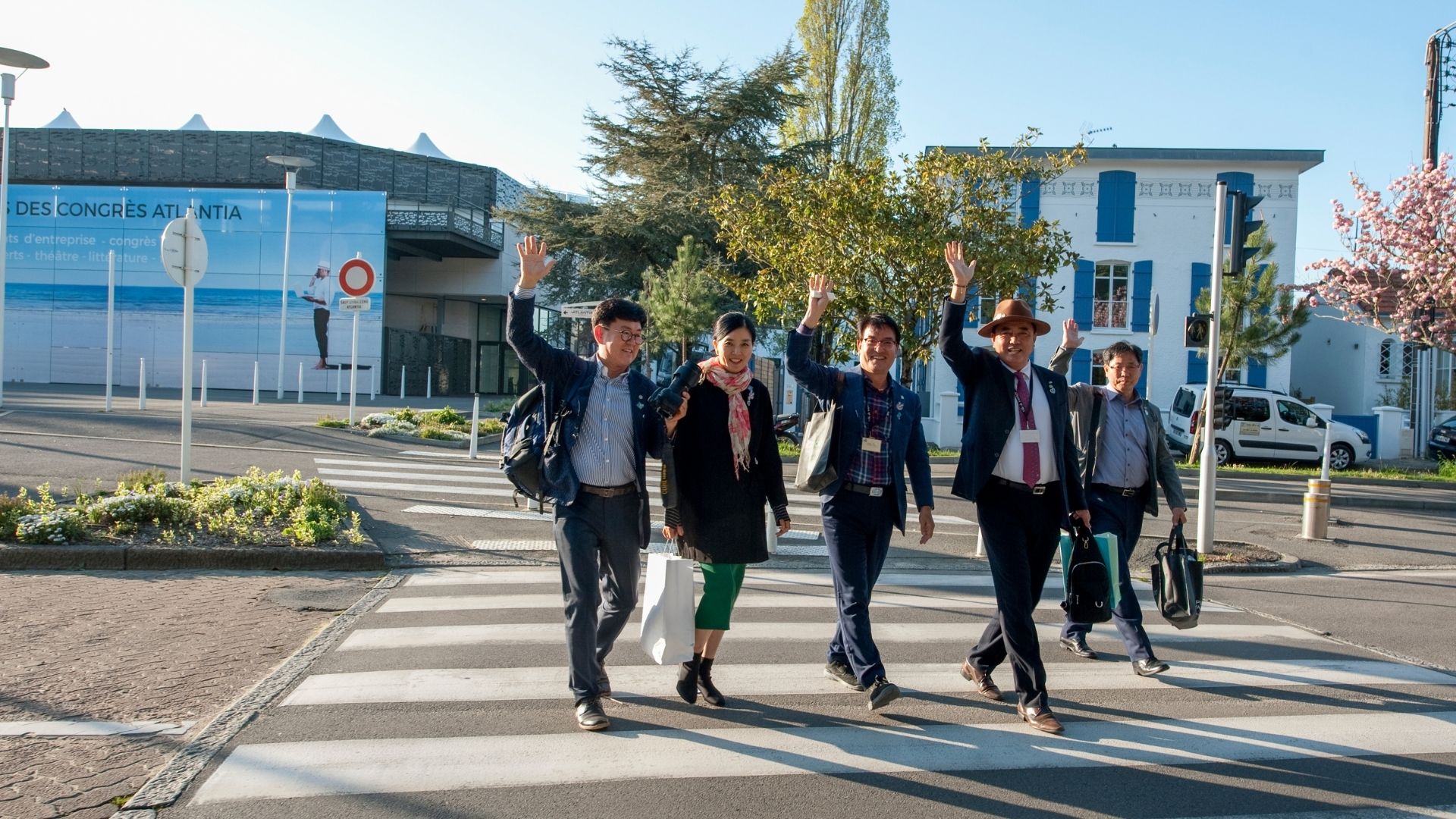 Groupe de personnes traversant la rue sur passage piéton devant le Palais des Congrès de la Baule